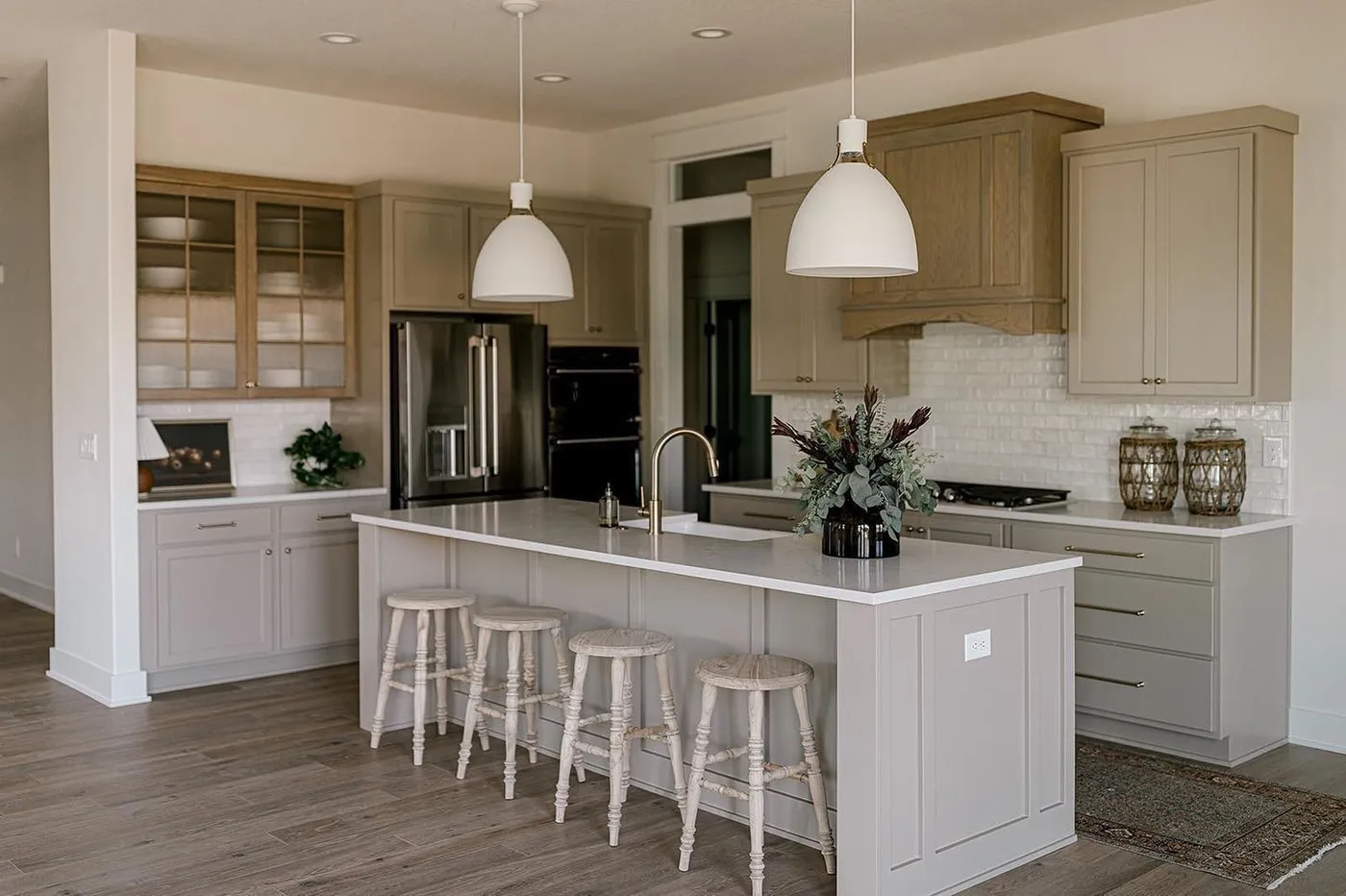 A bright kitchen with a white island and stools
